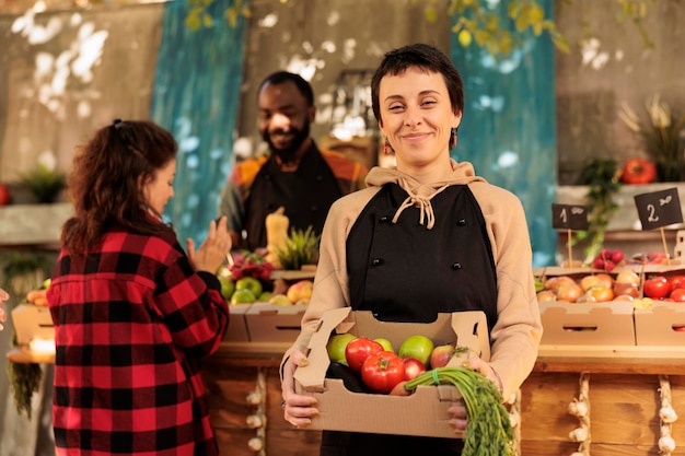 happy woman farmer selling organic produce local market health benefits locally grown food smiling stand vendor holding box full fresh seasonal fruits vegetables 482257 63566